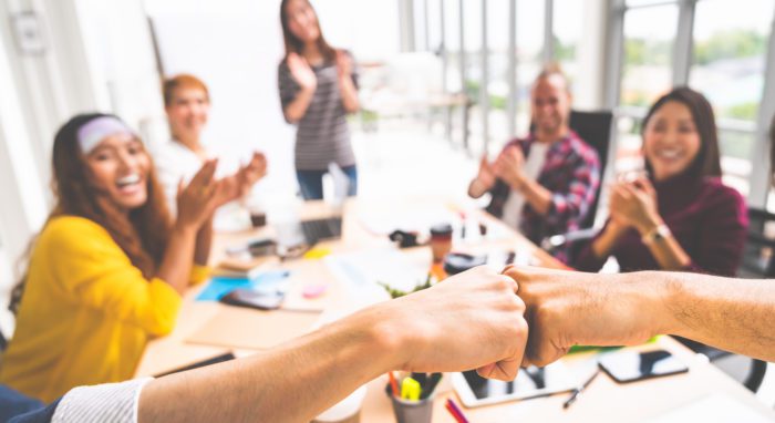 Business partners or men coworkers fist bump in team meeting, multiethnic diverse group of happy colleagues clapping hands. Teamwork cooperation, team building, or success business project concept