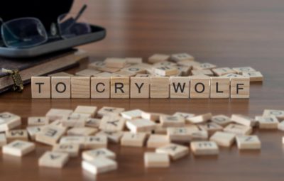 to cry wolf word or concept represented by wooden letter tiles on a wooden table with glasses and a book