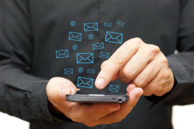 Businessman using smart phone with email icons around
