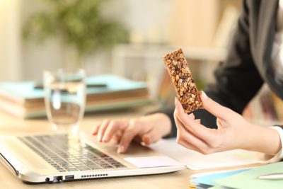 Entrepreneur hands holding snack bar working on laptop
