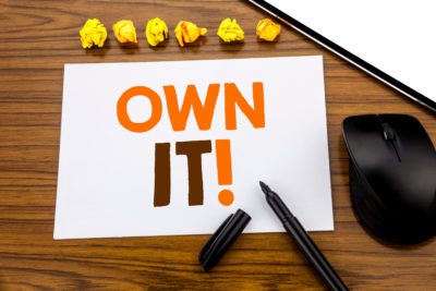 Conceptual hand writing text showing Own It Exclamation. Business concept for Ownership Control written on sticky note paper on wooden background with marker mouse and tablet office view.