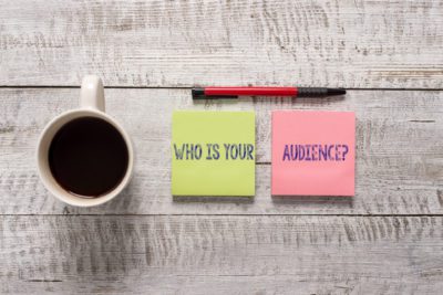 Text sign showing Who Is Your Audience Question. Business photo text who is watching or listening to it Stationary placed next to a cup of black coffee above the wooden table